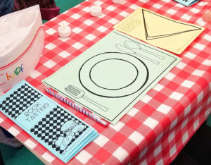 A sample book tasting place setting, including a placemat, napkin, menu, and chef's hat.